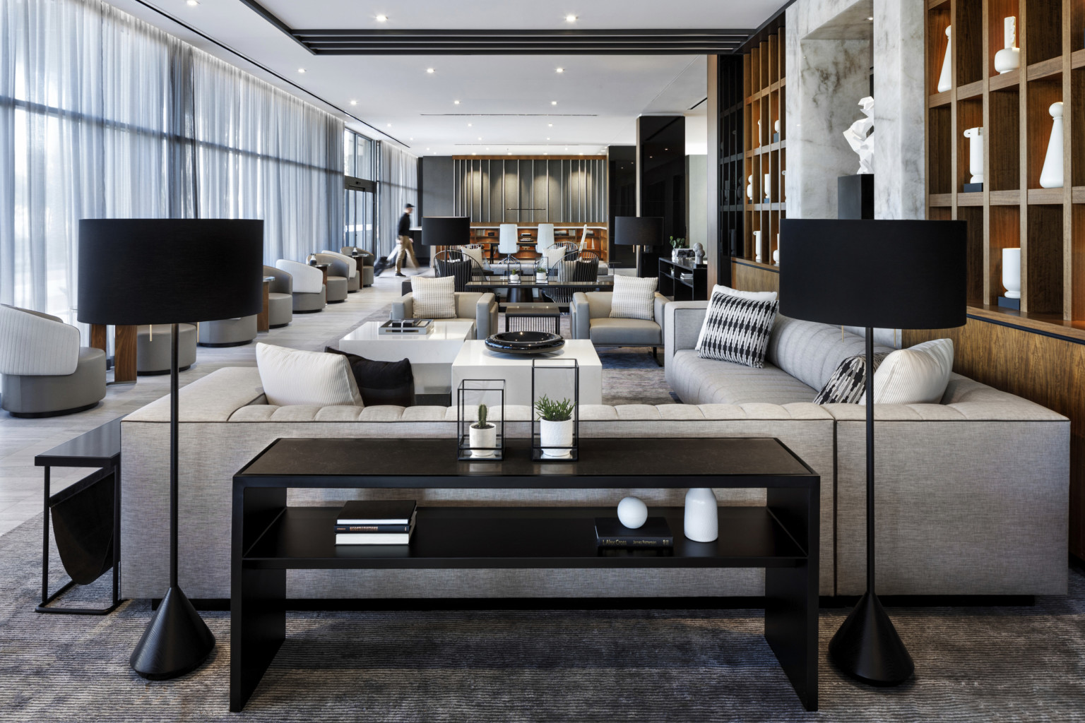 monochromatic hotel lobby with black floor lamps, black table and gray sofa