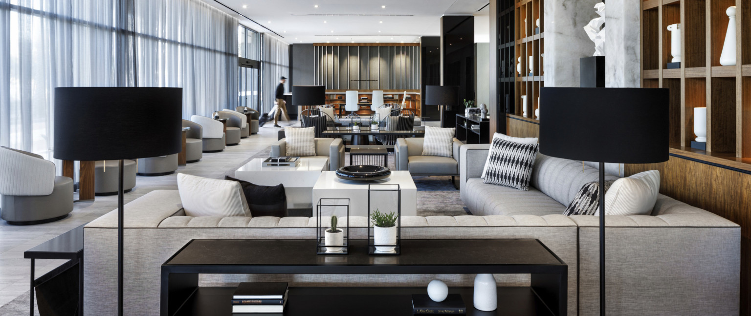 Mixed seating area in lobby with tables. Square wooden shelves to the right of the area, and floor to ceiling windows on left Mixed seating area in lobby with tables. Square wooden shelves to the right of the area, and floor to ceiling windows on left