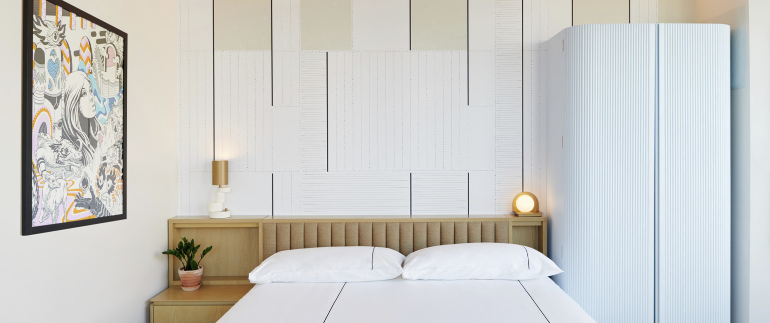 White bed with wooden storage headboard and beige panel upholstered headboard against stripe patterned wallpaper