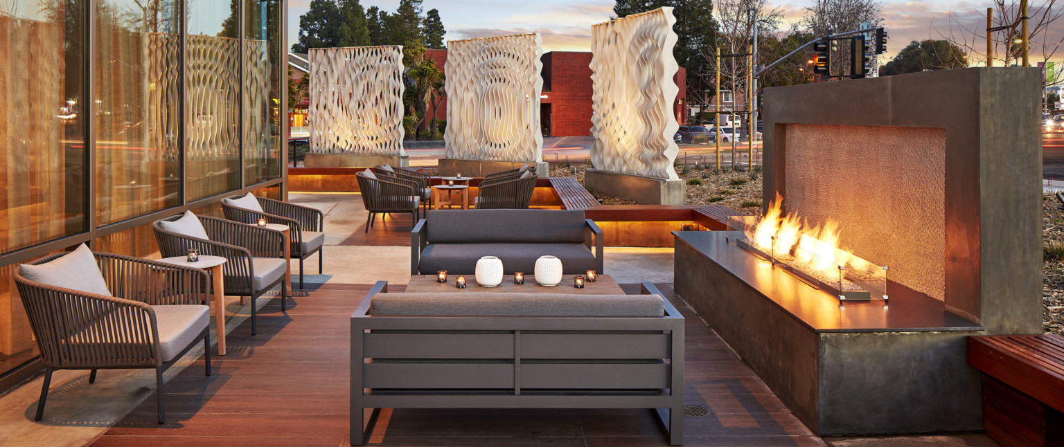 Outdoor seating area with couches and arm chairs in front of fireplace. Behind, more seating with 3 white organic sculptures Outdoor seating area with couches and arm chairs in front of fireplace. Behind, more seating with 3 white organic sculptures