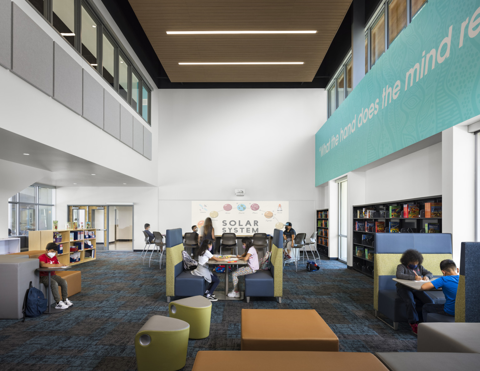 Double height seating area with shelves and large windows. A solar system hangs on the back wall. Interior windows above Double height seating area with shelves and large windows. A solar system hangs on the back wall. Interior windows above