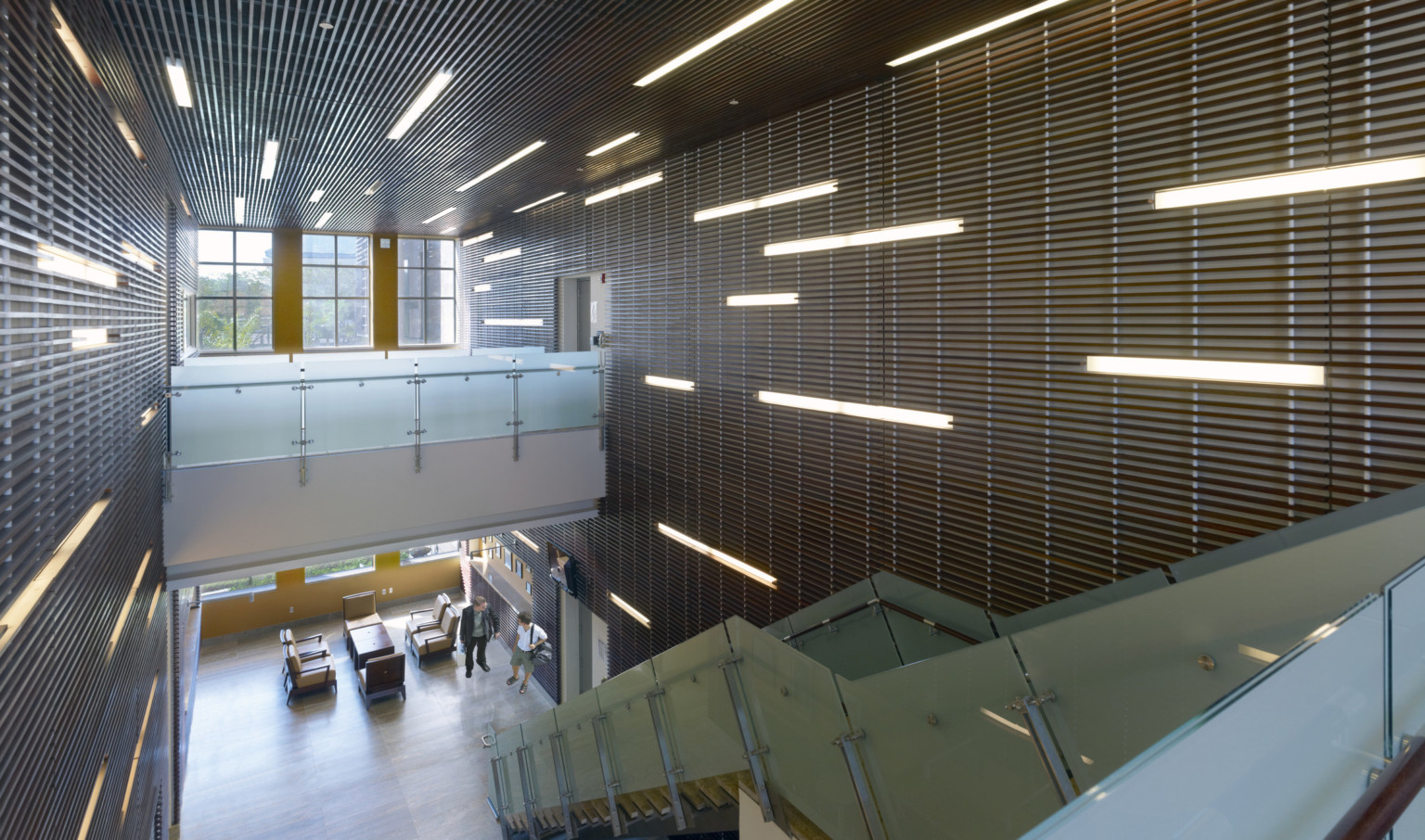 interior view looking down to lower level of U.S. Consulate with linear light features recessed into textured walls, ceiling