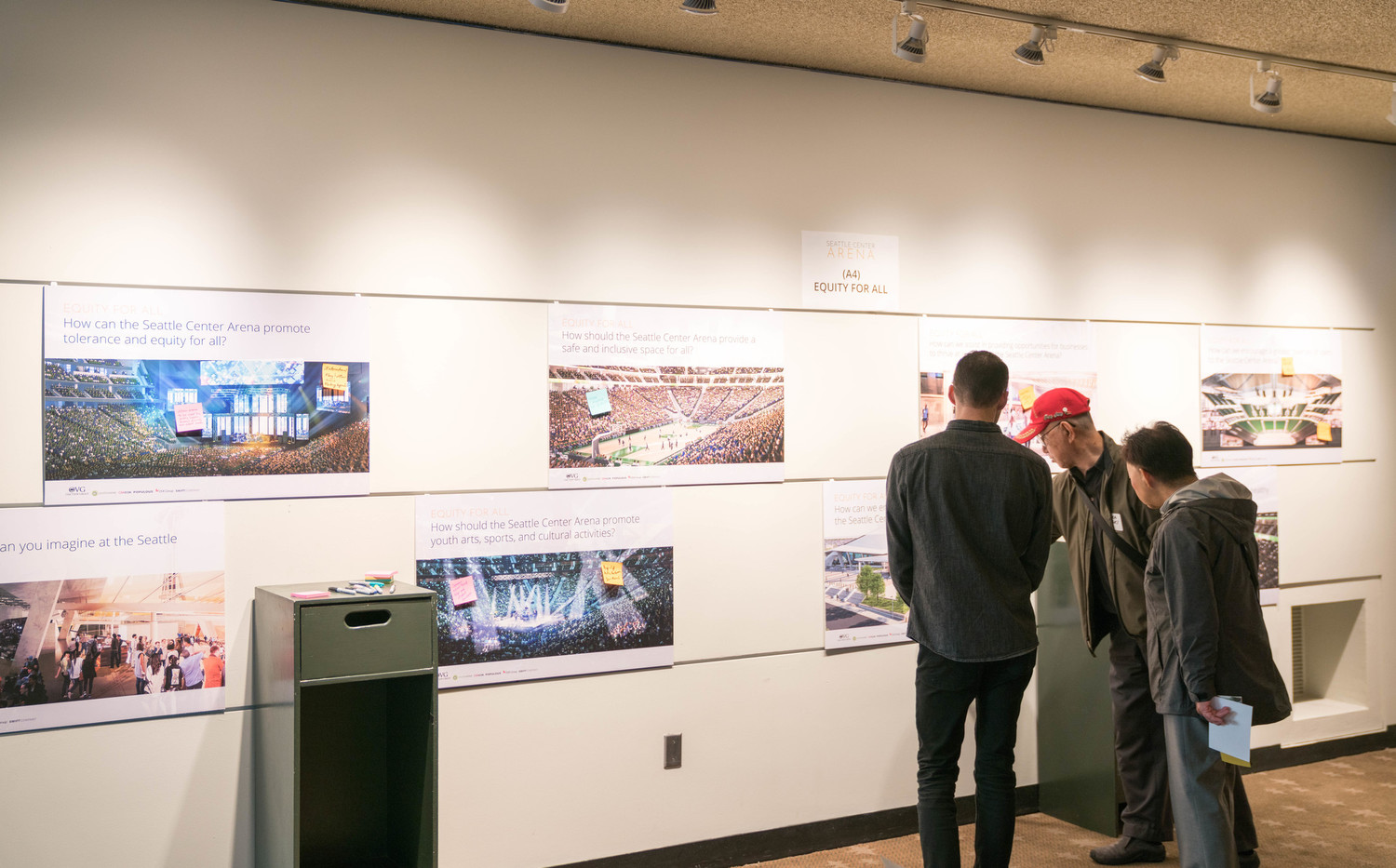 Three men pointing at a photo on gallery wall in Seattle Three men pointing at a photo on gallery wall in Seattle