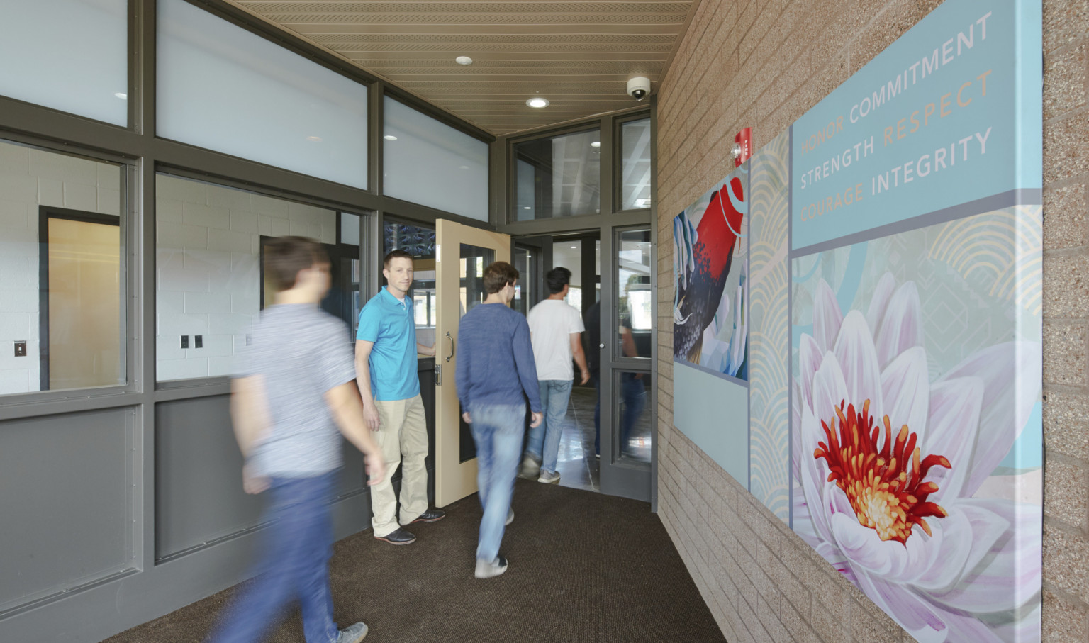 people walking through doorway with interior windows, left, blue and red artwork with values like integrity, respect, right people walking through doorway with interior windows, left, blue and red artwork with values like integrity, respect, right