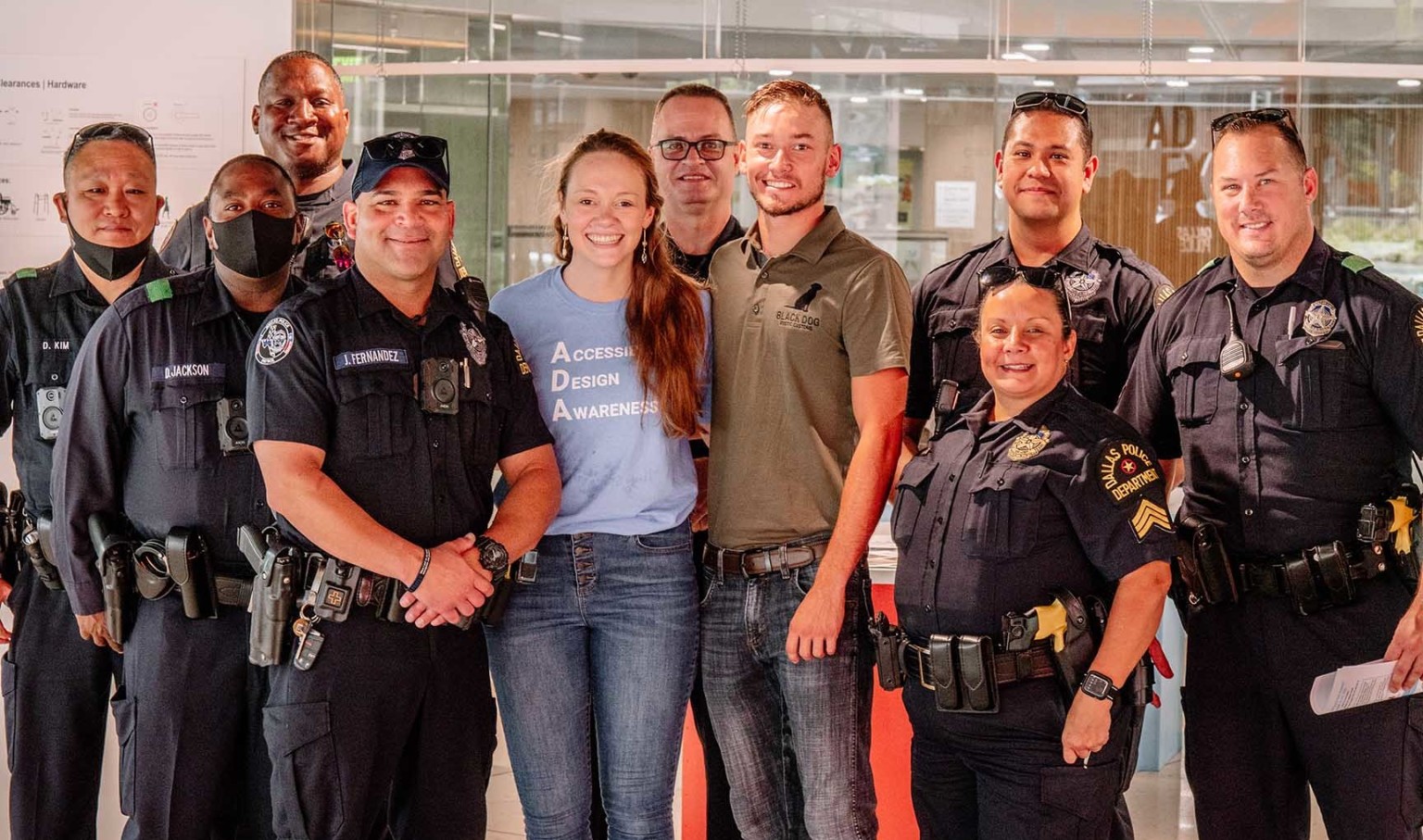 Amanda Collen, in blue Accessible Design Awareness shirt, surrounded by Dallas Police Department officers