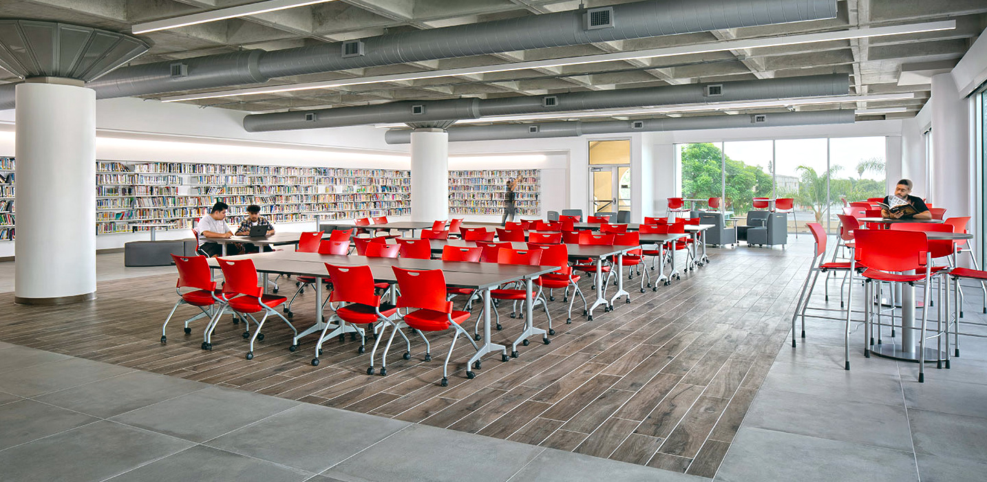 waffle slab ceiling wooden floor inset in concrete with media wall framing classroom with glass exterior wall and red chairs