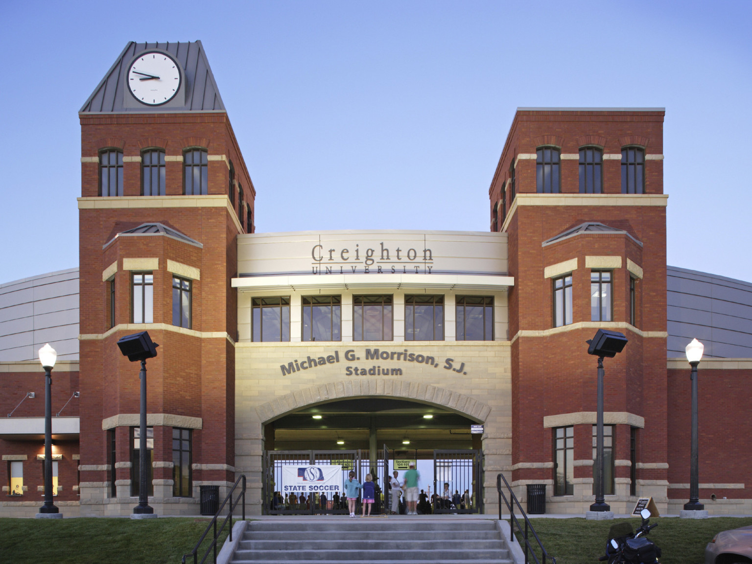 Stone arch entry labeled Creighton University Michael G. Morrison, S.J. Stadium, framed by brick towers. Clock on left tower