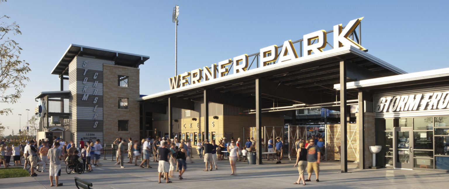 Werner Park entrance with signage above sheltered gates. Ticket windows line wall to left, with Storm Chasers written on side