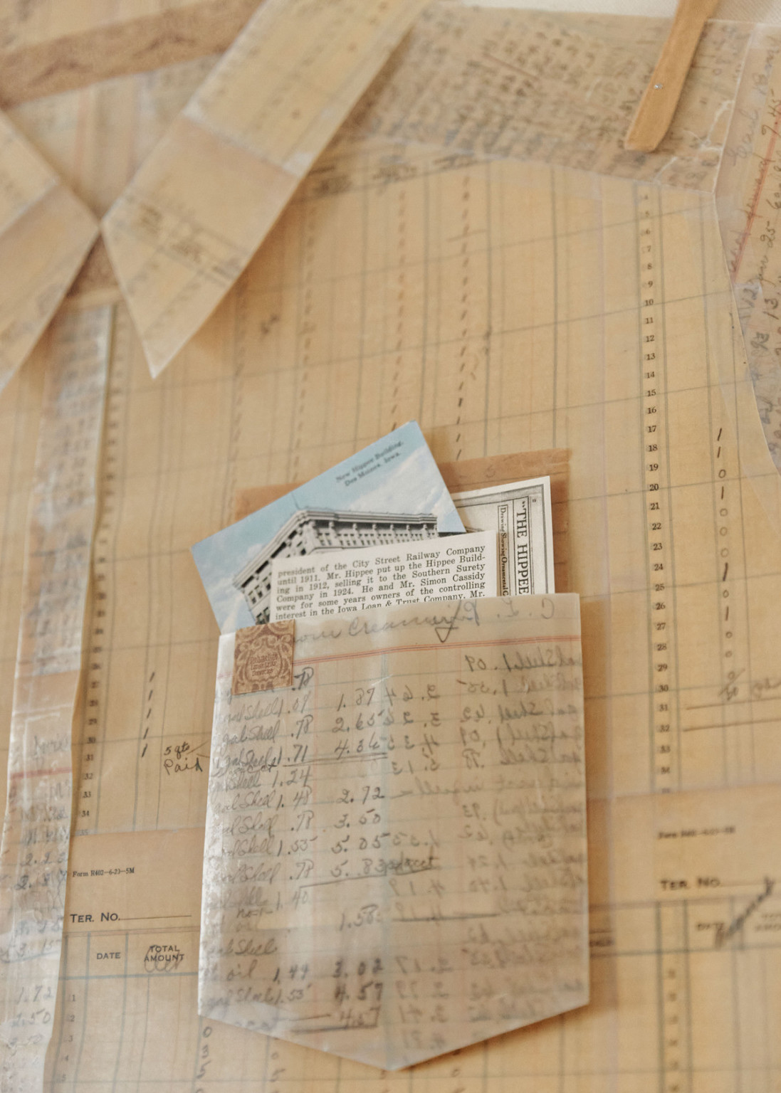 Closeup of old paper crafted into collared shirt with pocket containing slips of paper with building image and information