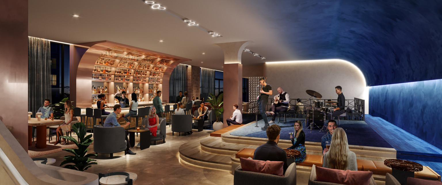 Bar in lobby section with curved roof, with blue carpeted stage opposite. Arm chair, bench, and bar seating available