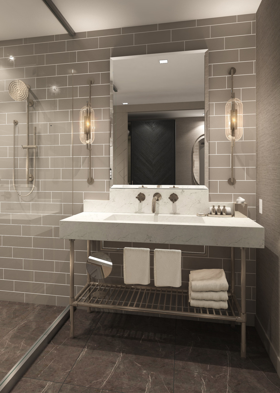 Grey tiled bathroom with marble sink over gold rack with towels. Mirror centered above between 2 oval lights on anchored rods