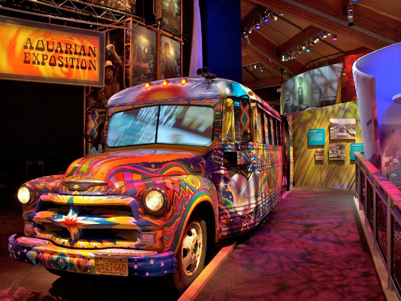 Bus with multicolored abstract painting inside a room with textural colored lighting below a sign reading Aquarian Exposition