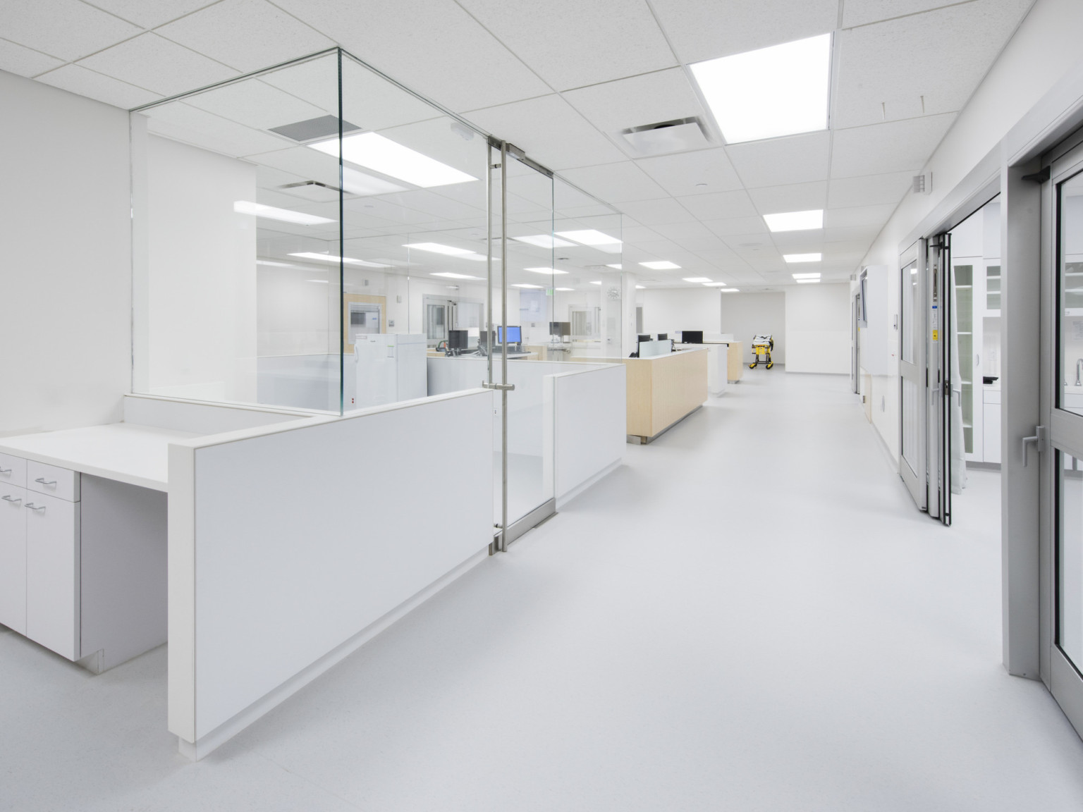 Bright white emergency room nurses stations opposite patient rooms have glass walls for visibility