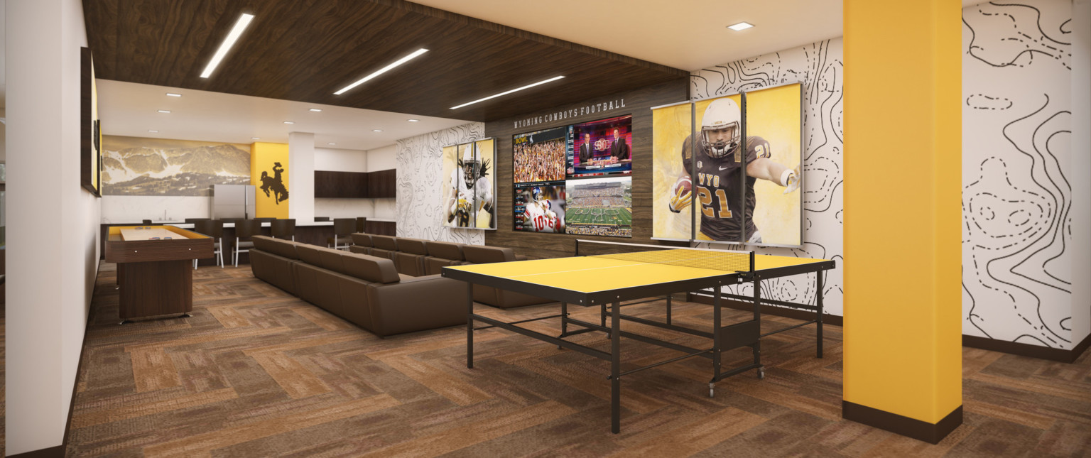 Couches face wood wrapped accent wall with 4 screens below Wyoming Cowboys Football sign in white room with yellow accents