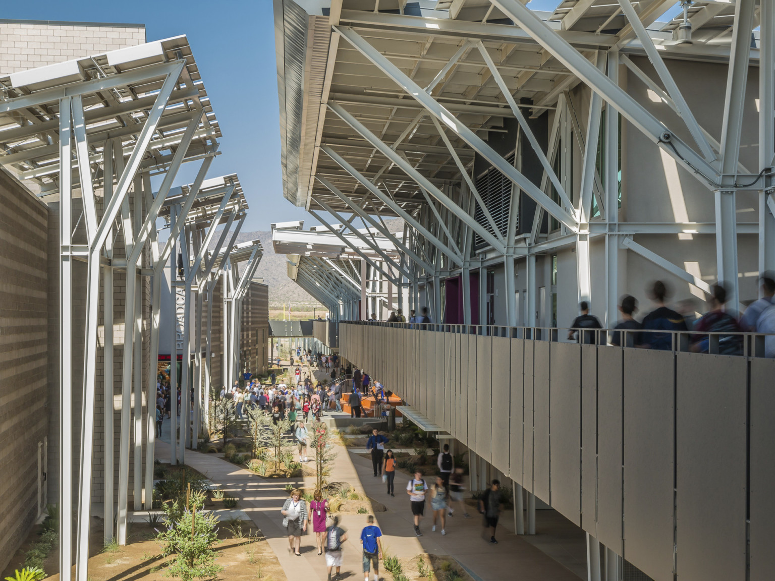 A second floor exterior partially covered walkway is framed on both sides by exposed structural beams