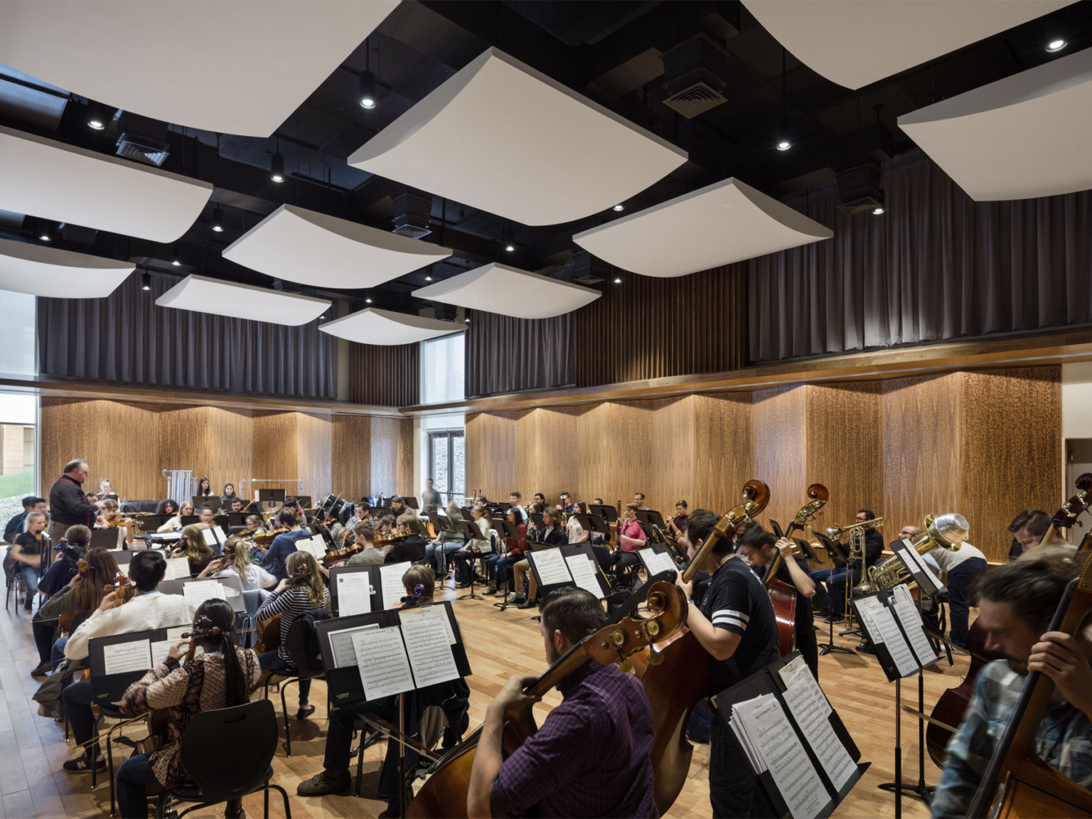 Student musicians rehearsing in studio with angled wood panels on the walls and white acoustical sound panels on the ceiling
