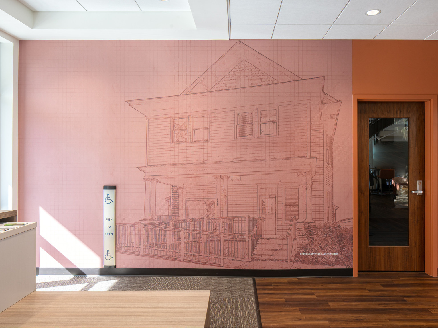 Pink mural with mural of lining drawing of a house on a grid pattern next to an orange wall and door