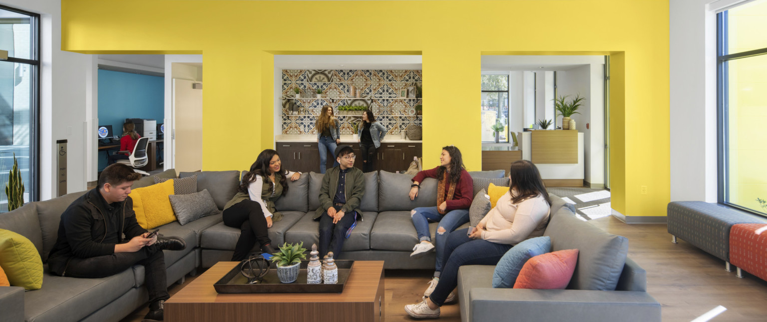 Yellow seating area off entry with large U shaped sectional and coffee table. Recessed counter in center of wall with tiles Yellow seating area off entry with large U shaped sectional and coffee table. Recessed counter in center of wall with tiles