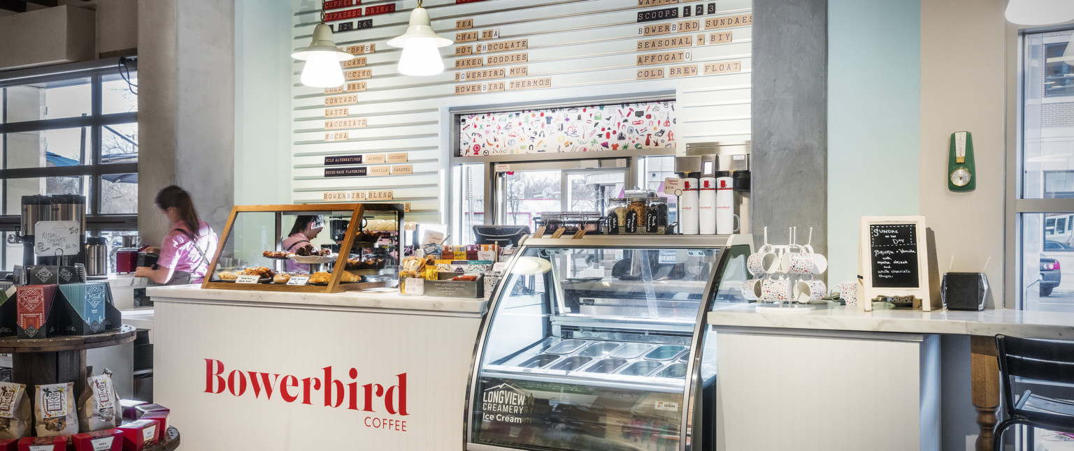 White Bowerbird Coffee counter with marble top and wood pastry display box. Between sections is a Longview Creamery cooler
