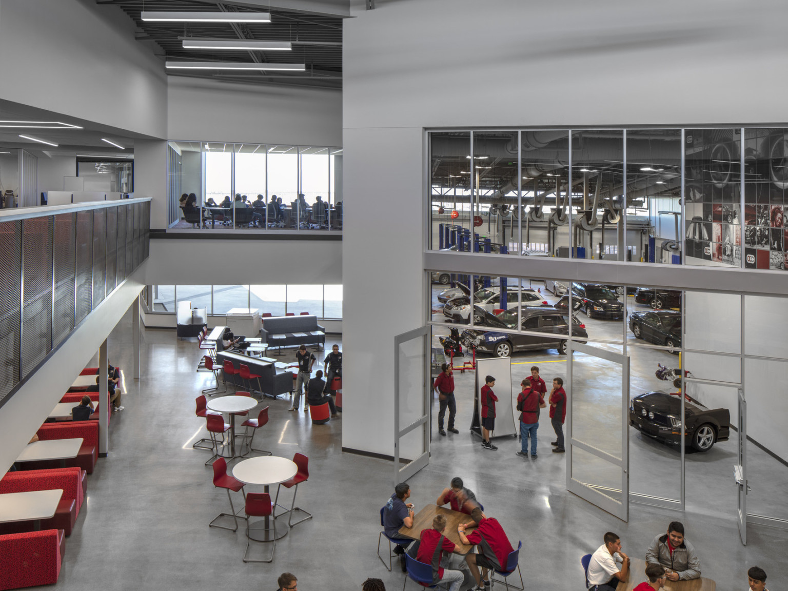 View from 2nd floor balcony overlooking seating and glass entrance to double height auto industry and mechanic specific lab
