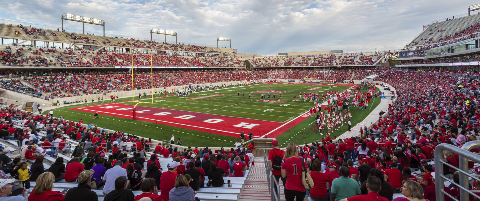 Football stadium on game day with fans in red on grey bleachers. Red end zone with Houston written in white