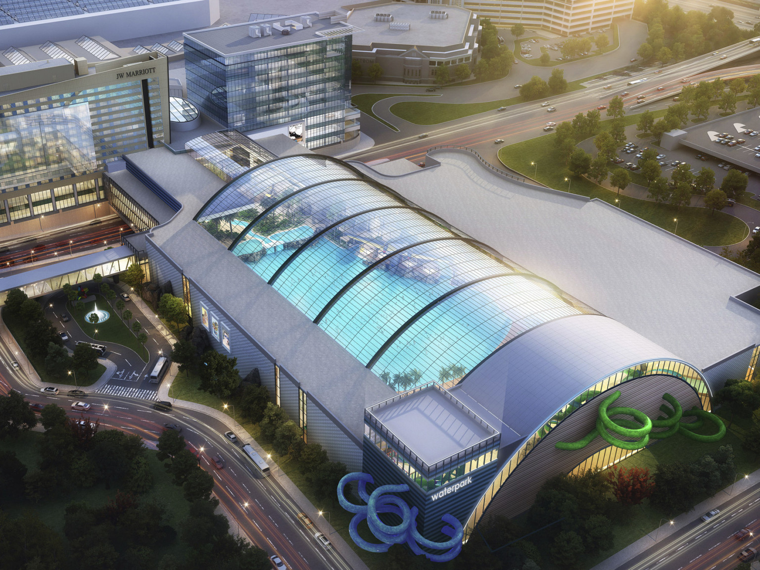 Aerial view of indoor waterpark with arching skylights over roof. Blue and green water slides curl out sides of grey building Aerial view of indoor waterpark with arching skylights over roof. Blue and green water slides curl out sides of grey building