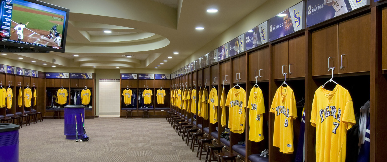 Locker room with wood cabinets above purple space for hanging gear. Yellow Jerseys hang in front of each, player's name above