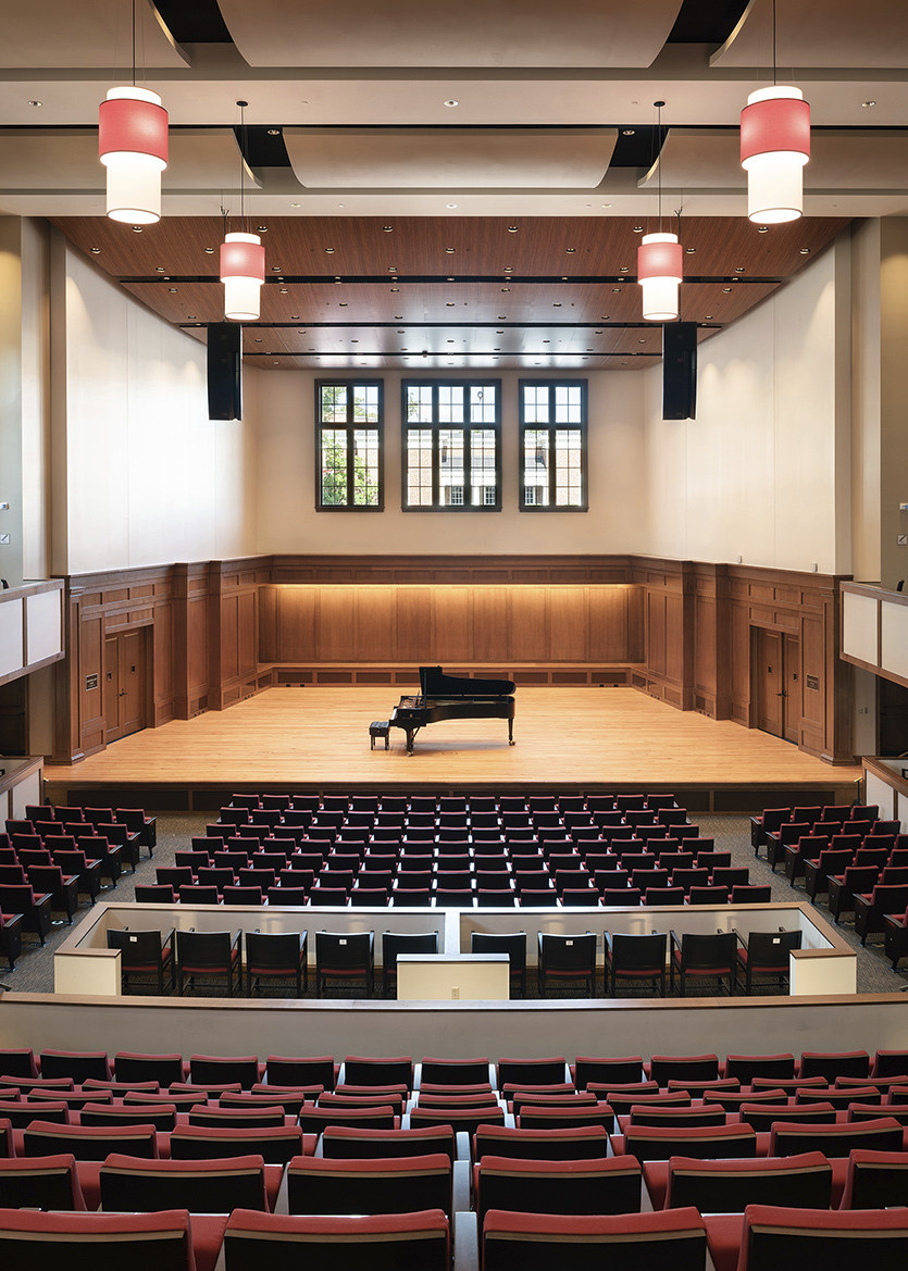 theater with red upholstered seating convex acoustic panel ceiling red lantern pendants and wooden recital stage with piano