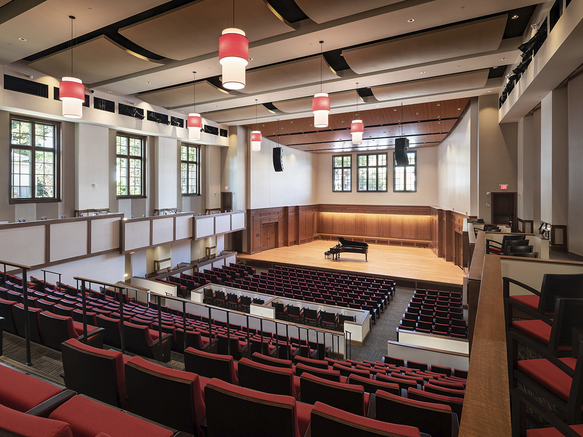 theater with red upholstered seating wood trim theater boxes convex acoustic panel ceiling and wooden recital stage