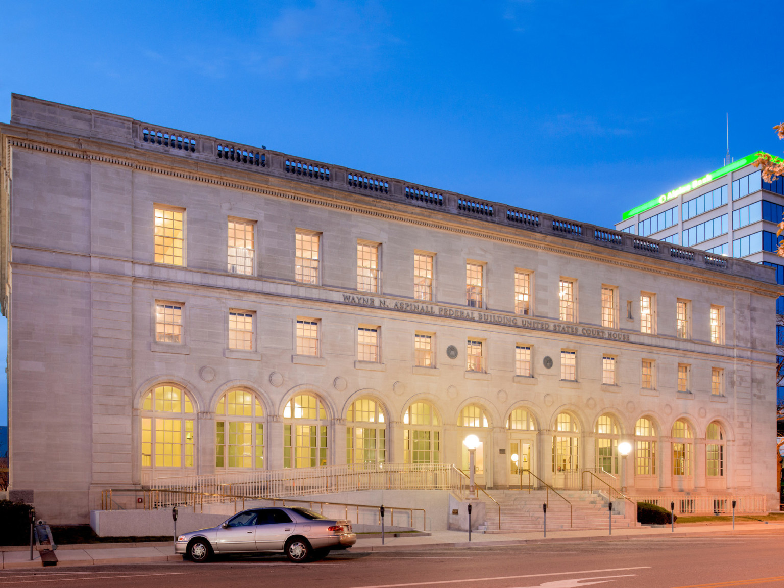 Illuminated entry of limestone Italian Renaissance Revival style building with arch shaped windows on first floor