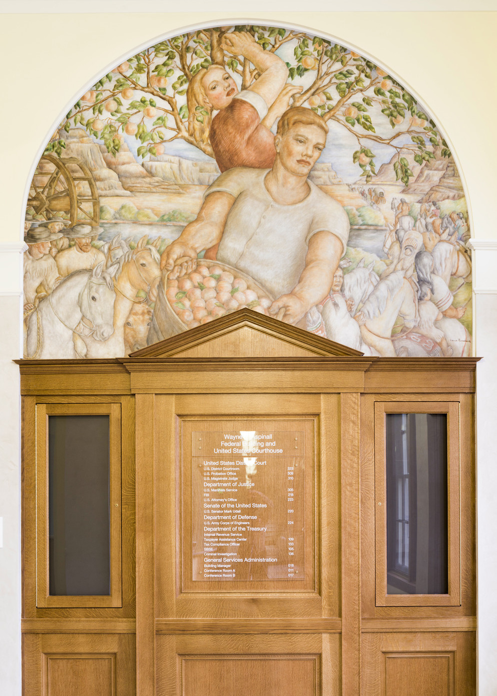 Office wayfinding sign on wood under arch with the mural Peach Harvest by Louise Ronnecheck