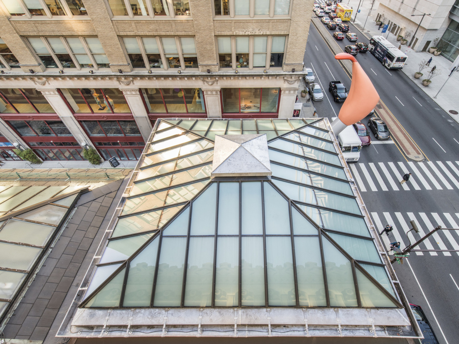 Pyramid shaped skylight seen from above, triangular sections are divided with contrasting trim, a metal pyramid sits on top