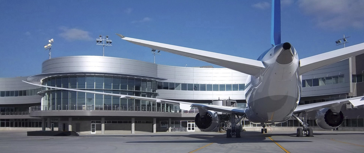 Boeing Everett Delivery Center curving building with glass and silver panel facade with elevated walkway wraps around plane