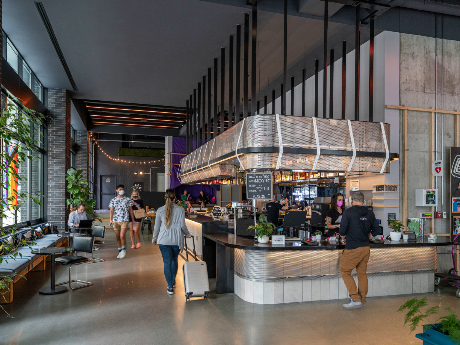 Coffee shop in hotel lobby with white and grey wrap around counter, hanging angular light follows the shape of the counter