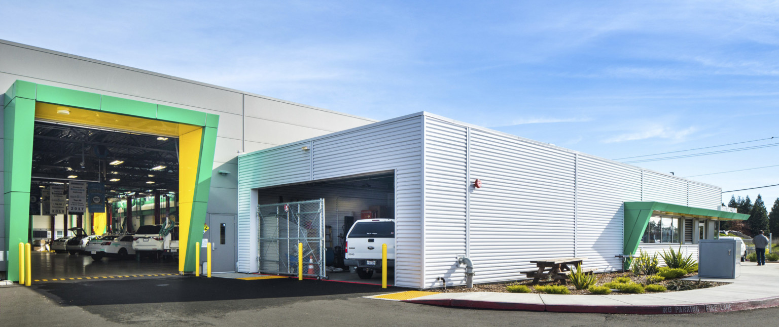 Exterior of garage door entrance to previous room with green and yellow awning, left. Main building entrance to right