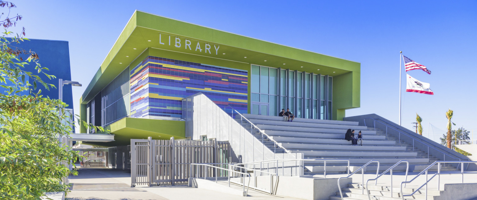 Corner view of lime library, multicolor tile wraps around left side between floor to ceiling windows. Grey steps in front
