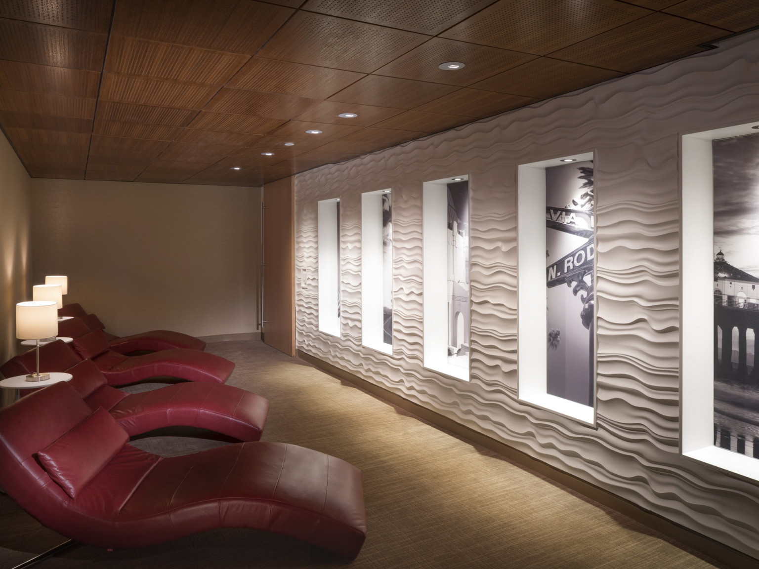 red reclining chairs in a healing spa room with black and white artwork and wood ceilings