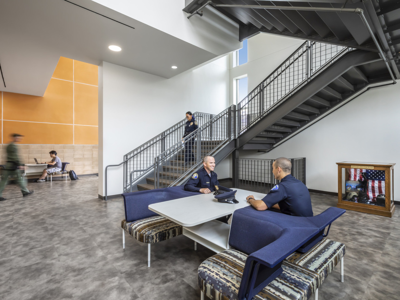 Two officers sit at a 4 person table with individual spaces at the base of a stairwell
