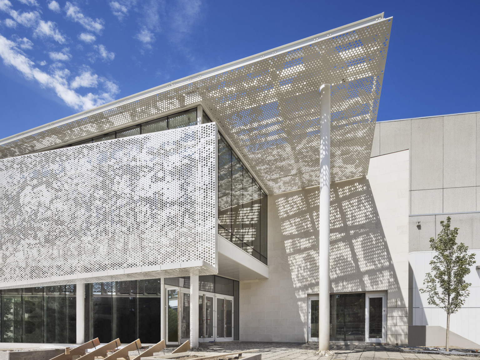 Organic design in translucent awning provides shade and shadow design in the entry of light colored building