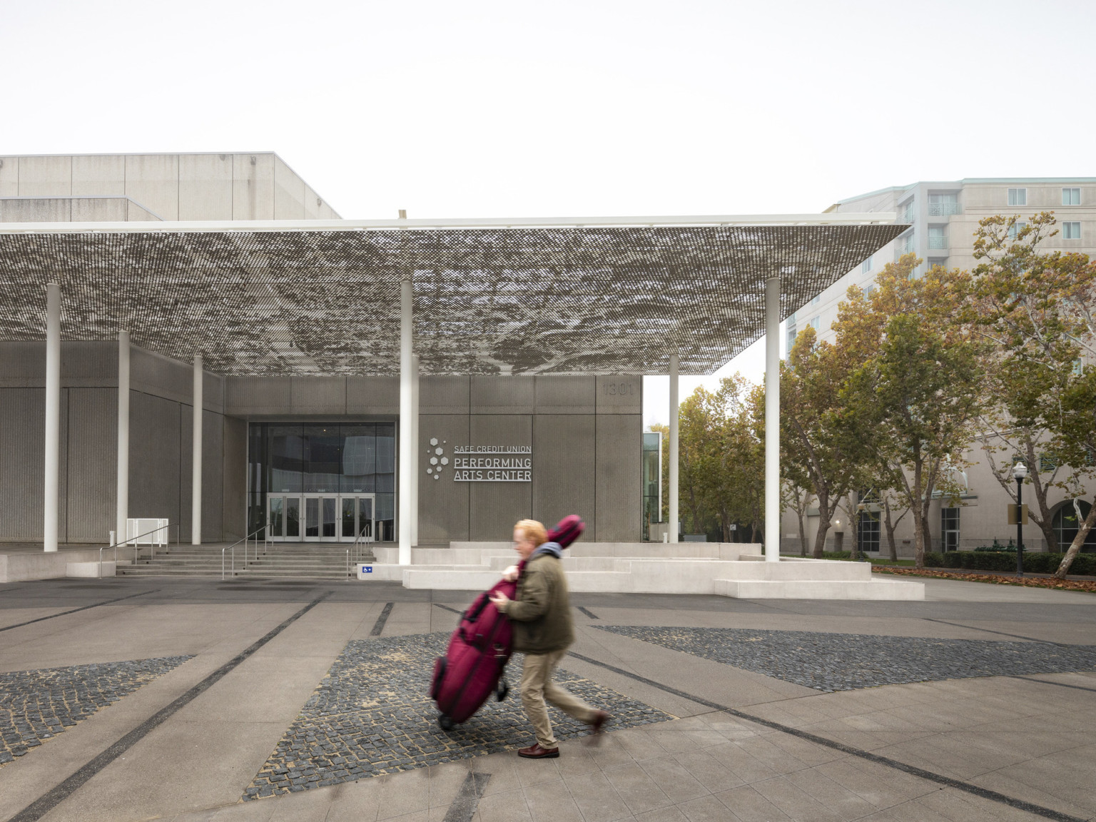 Walkway with geometric shapes in front of theatre entrance with a white perforated awning