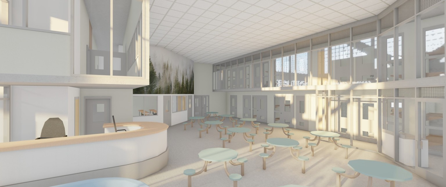 White room with 2 levels of grey doored cells over central area with tables and attached chairs. A mural of trees on top left