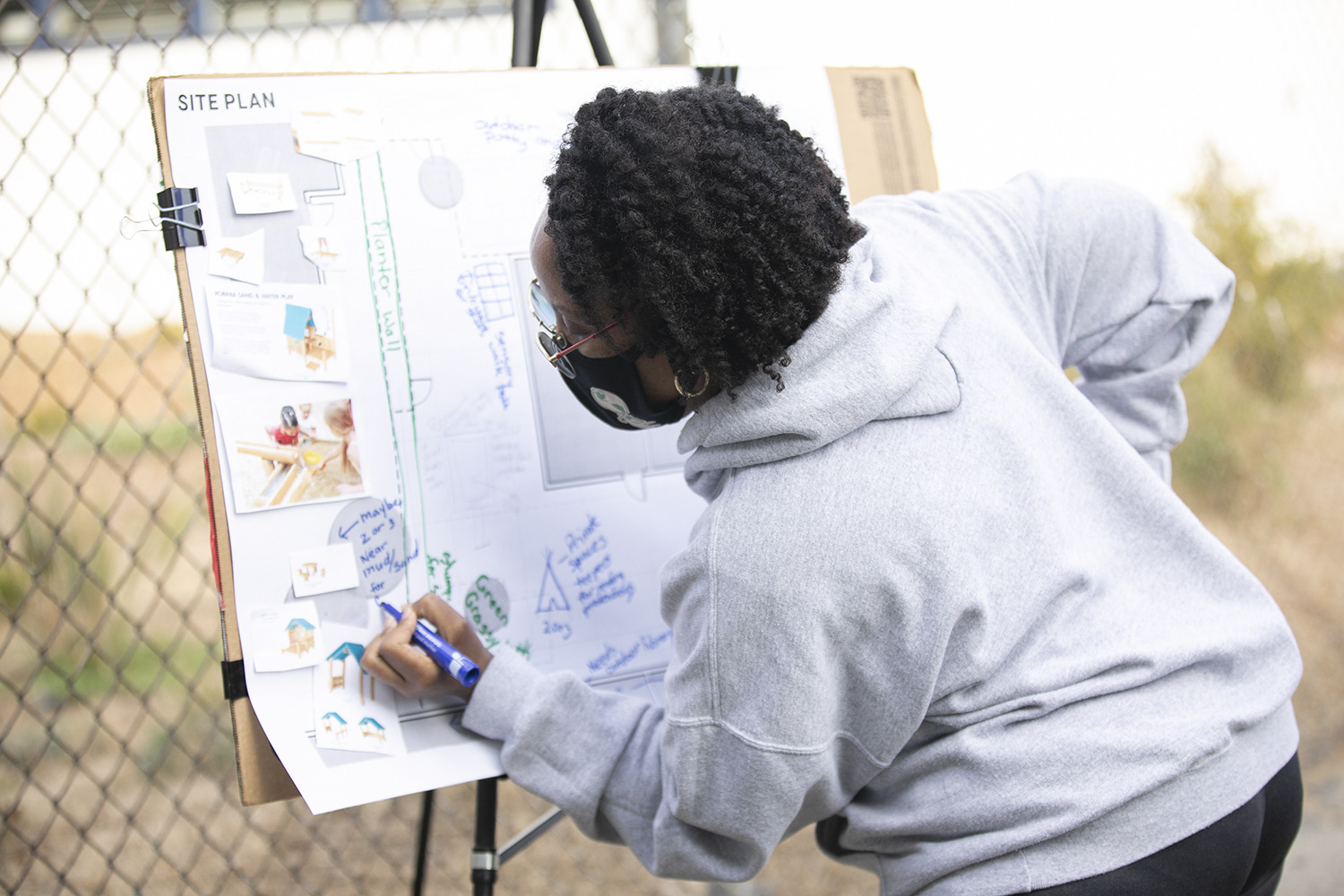 woman writing feedback on a board at a community meeting with architects