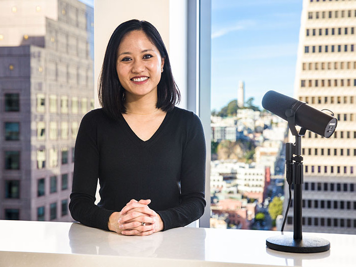 a woman sitting at a desk with a podcast microphone in picture