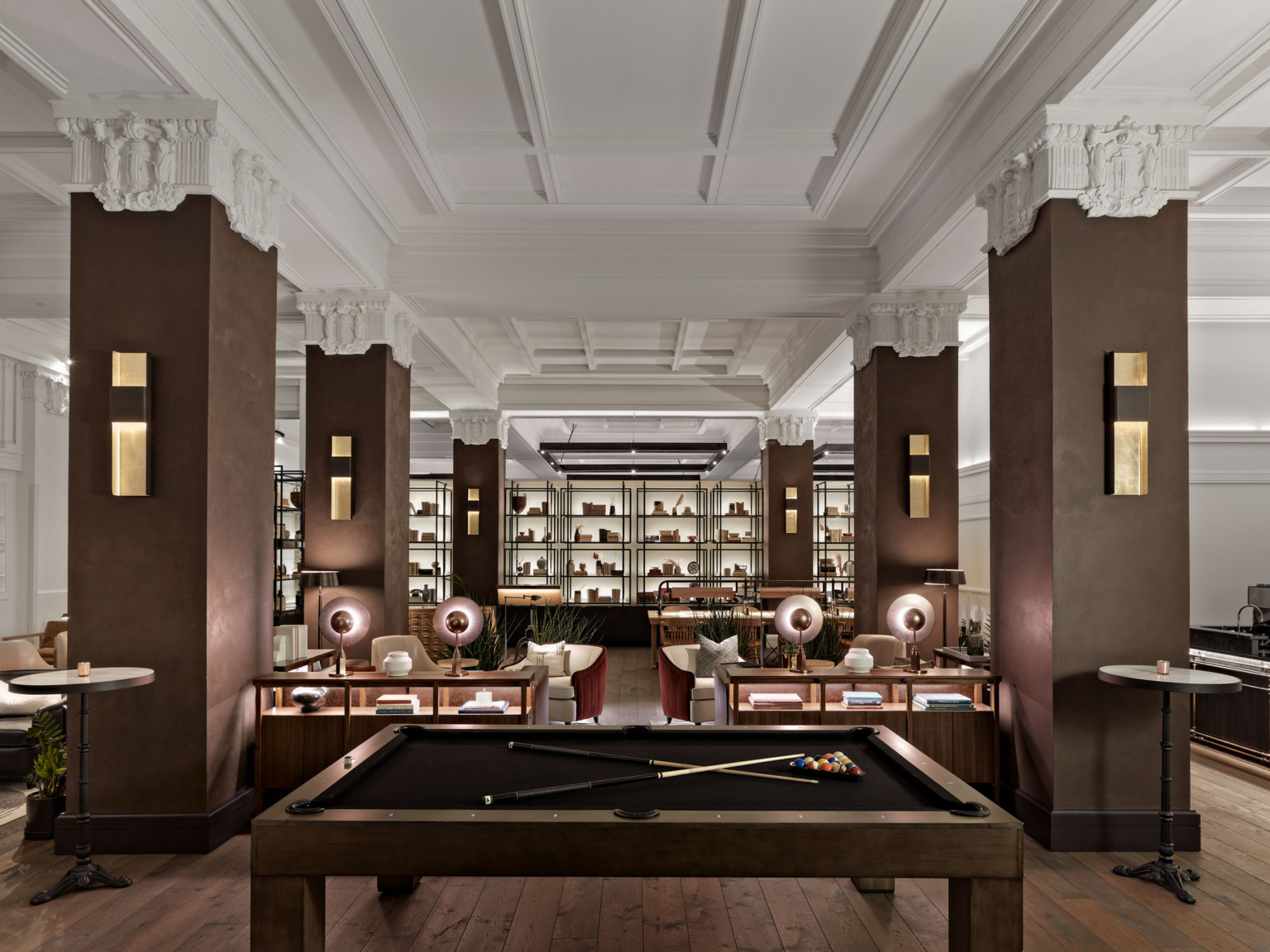 he Surety Hotel with billiard tables and wood pillars and white Corinthian capitals in room with recessed ceiling details