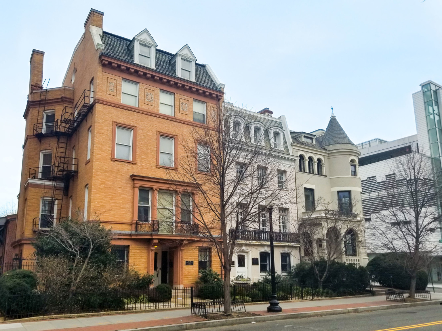 historic row houses in Washington DC, the leftmost being a warm orange revival brick façade. Turret on far right building