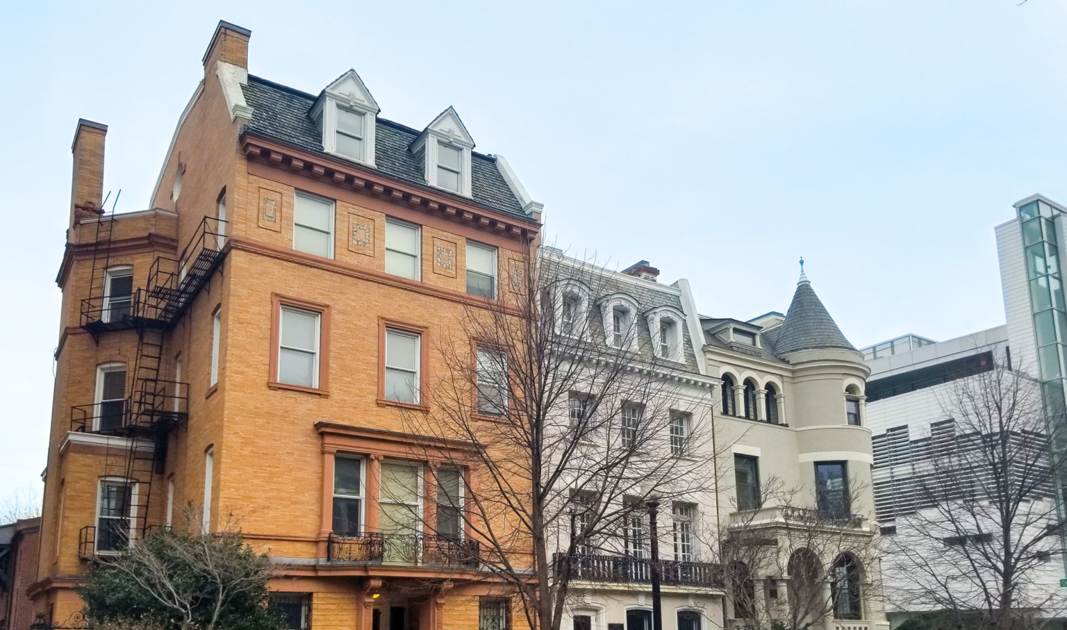 historic row houses in Washington DC, the leftmost being a warm orange revival brick façade. Turret on far right building