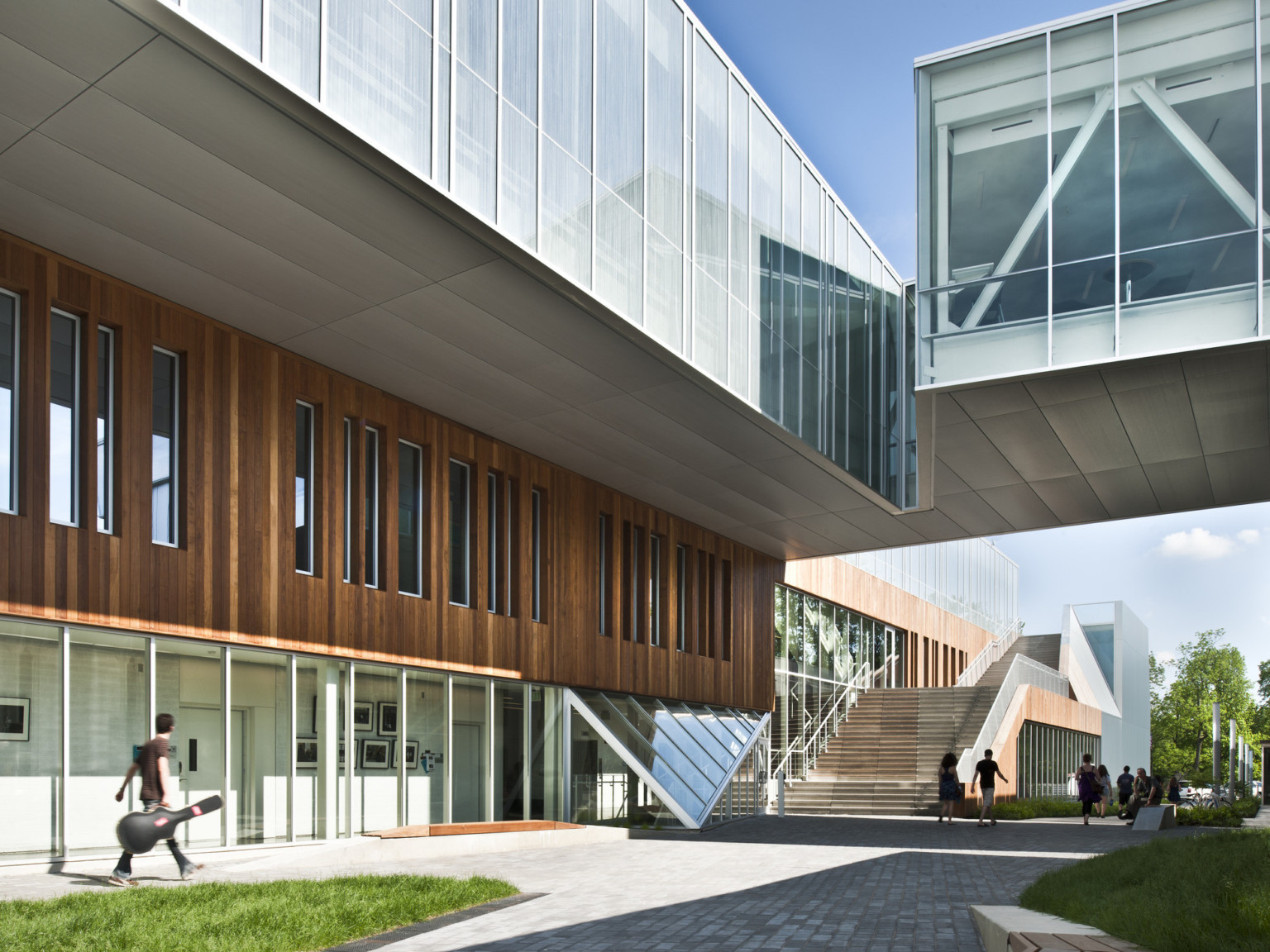 Partially covered walkway between buildings, building at left has first floor window walls below wood panels Partially covered walkway between buildings, building at left has first floor window walls below wood panels