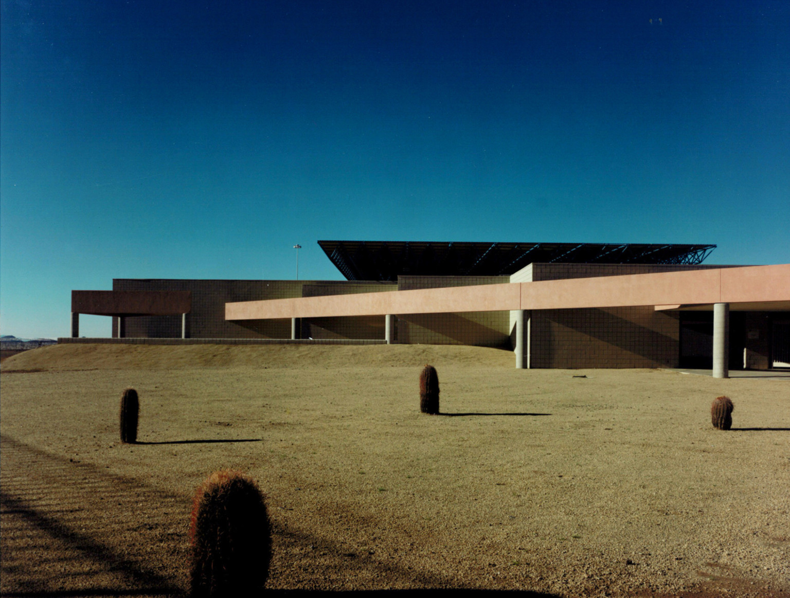 Federal Correctional Institution in Phoenix, a modern angular building with columns supporting beige overhang and rooftop panel Federal Correctional Institution in Phoenix, a modern angular building with columns supporting beige overhang and rooftop panel