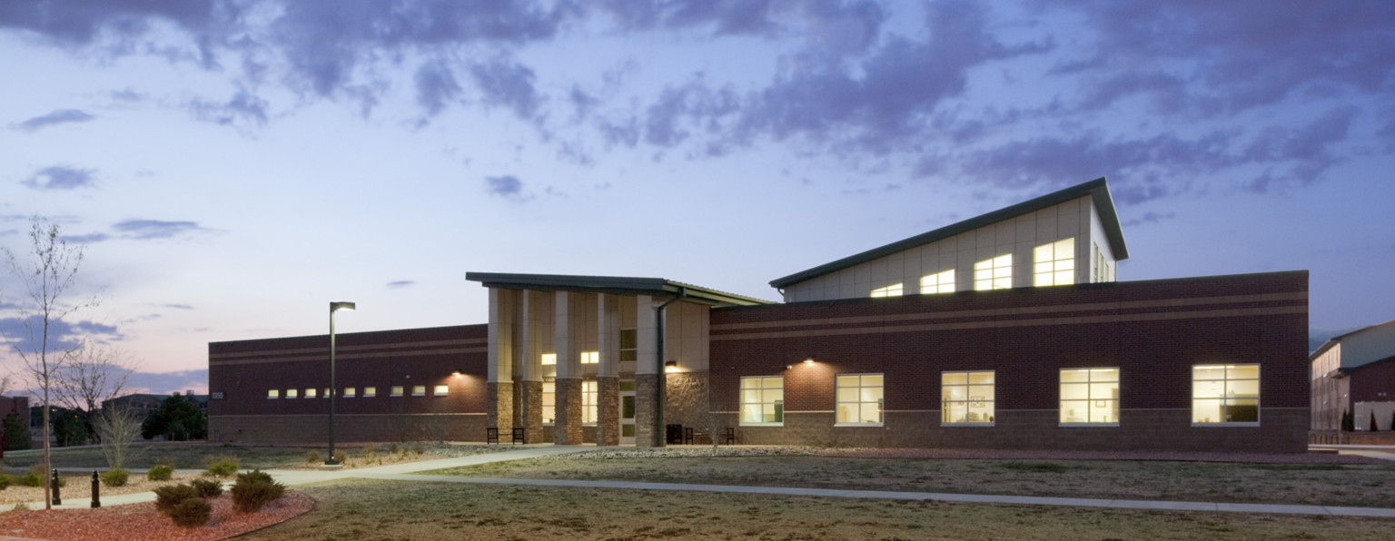 building with four distinct volumes, two red brick wings divided by asymmetrical stone and white central entry with columns building with four distinct volumes, two red brick wings divided by asymmetrical stone and white central entry with columns
