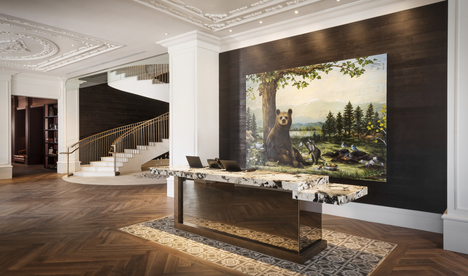 Reception desk with white and black marble counter in white lobby in front of recessed wood wall with painting of a bear Reception desk with white and black marble counter in white lobby in front of recessed wood wall with painting of a bear